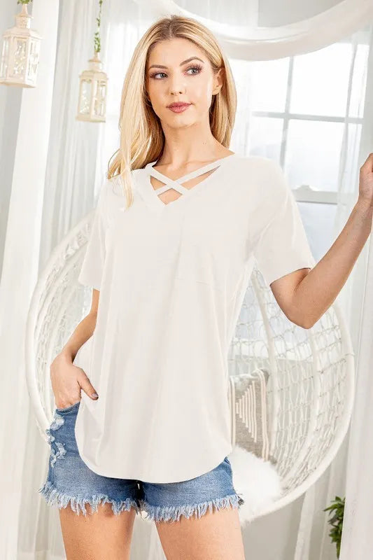 Woman wearing a white top and denim shorts in a bright room with sheer curtains.