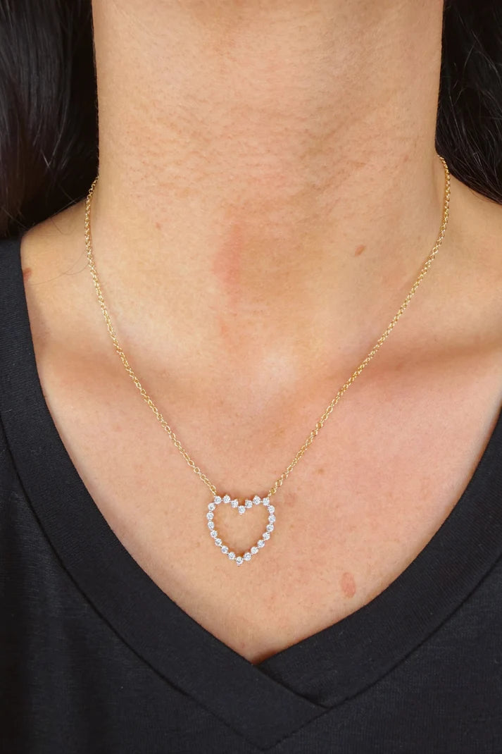 Woman wearing a gold chain with a single heart at the center.