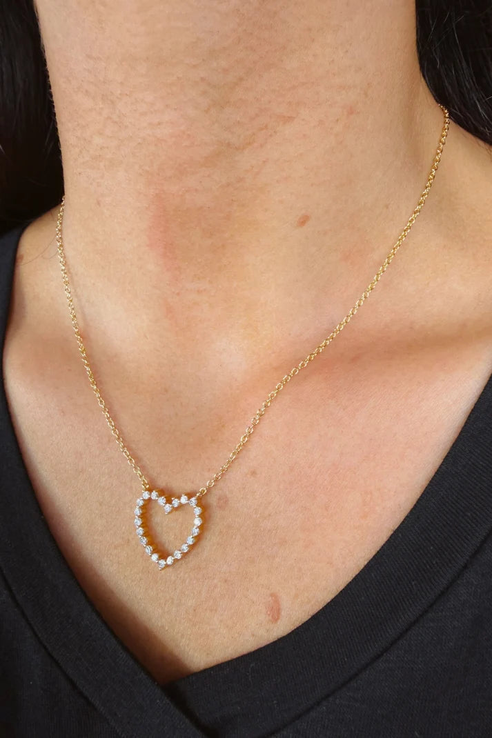 Woman wearing a gold chain with a single heart at the center.
