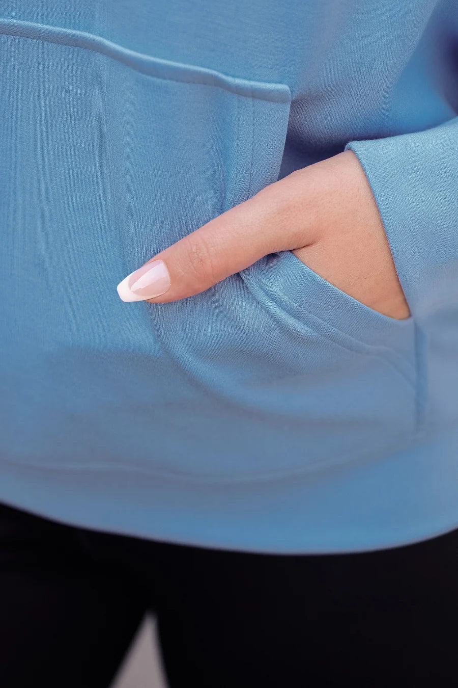 Hand with a manicured nail touching a blue fabric surface