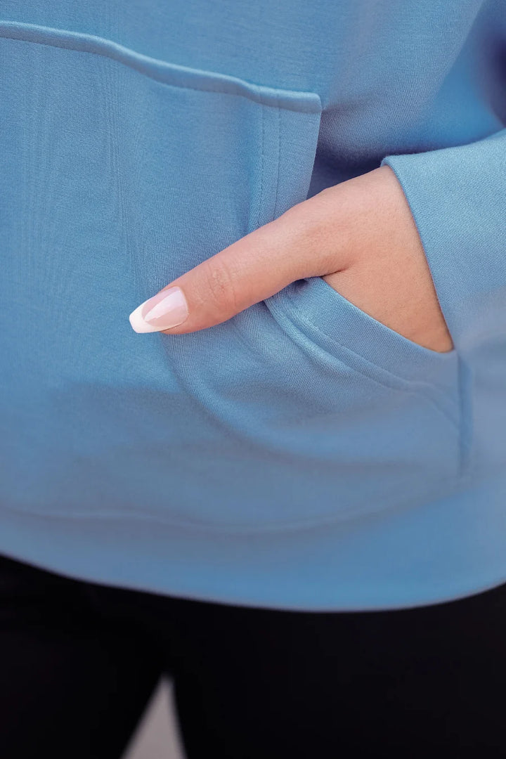 Hand with a manicured nail touching a blue fabric surface
