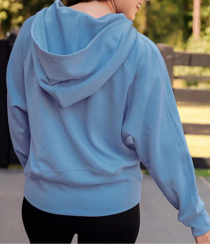 Woman wearing a light blue hoodie with trees in the background