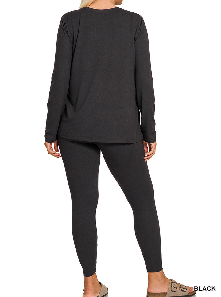A woman shown from the back wearing a black long-sleeve top and black leggings, standing against a plain white background. A small text label in the bottom right corner reads &