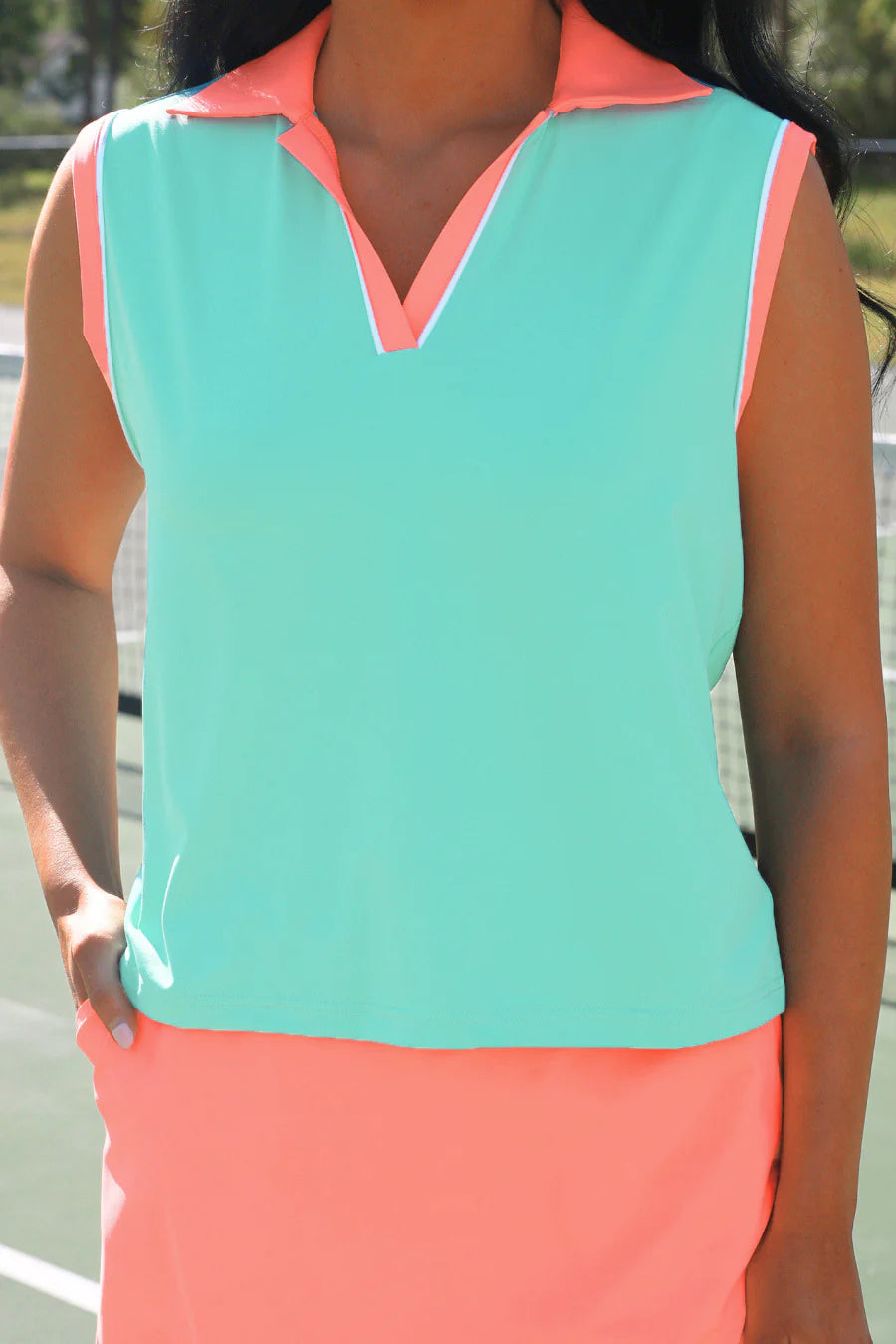 Person wearing a sleeveless top with mint and coral colors on a blurred background