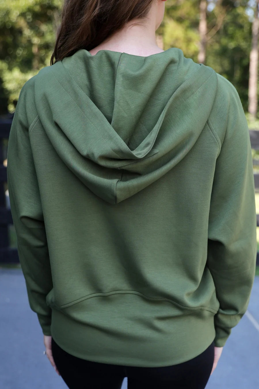Person wearing a n olive hoodie with a blurred background