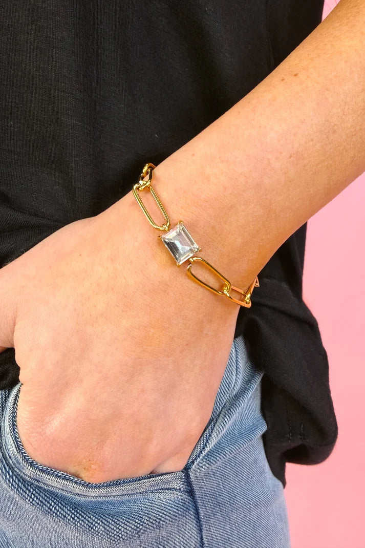 Woman wearing a paper clip chain bracelet with a gem.