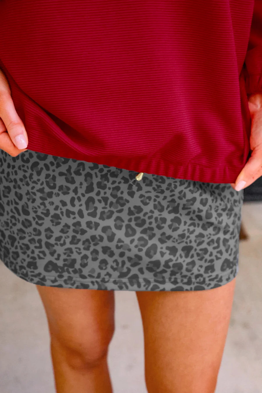 Person wearing a red top and gray leopard print skirt.