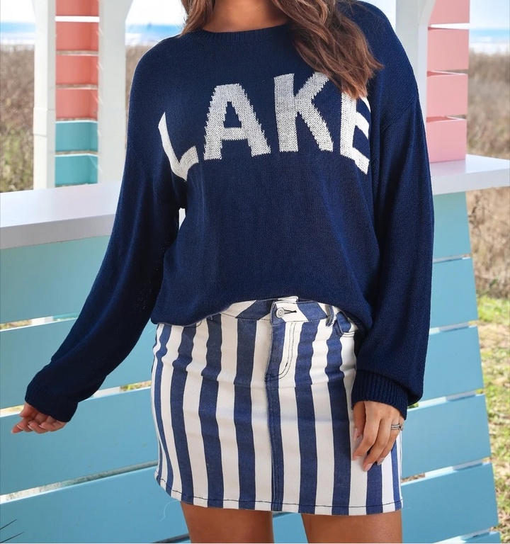 Model wearing a navy “LAKE” sweater with a navy-and-white striped denim mini skirt.