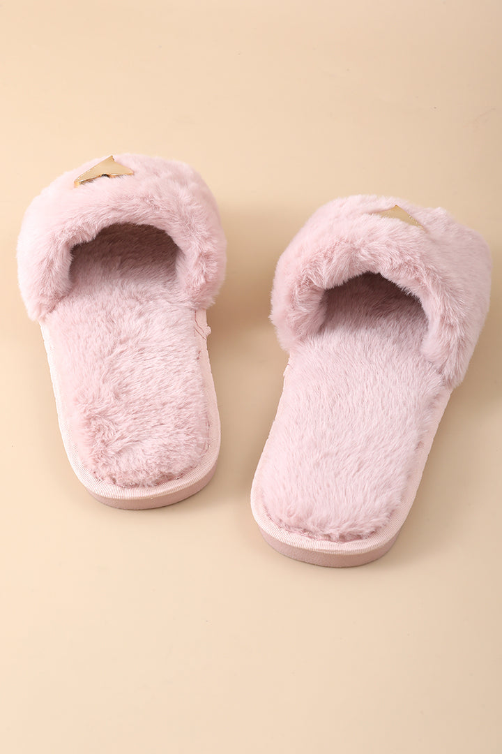 A pair of fluffy light pink slip-on slippers with a small gold bow detail on the top, displayed on a solid beige background.