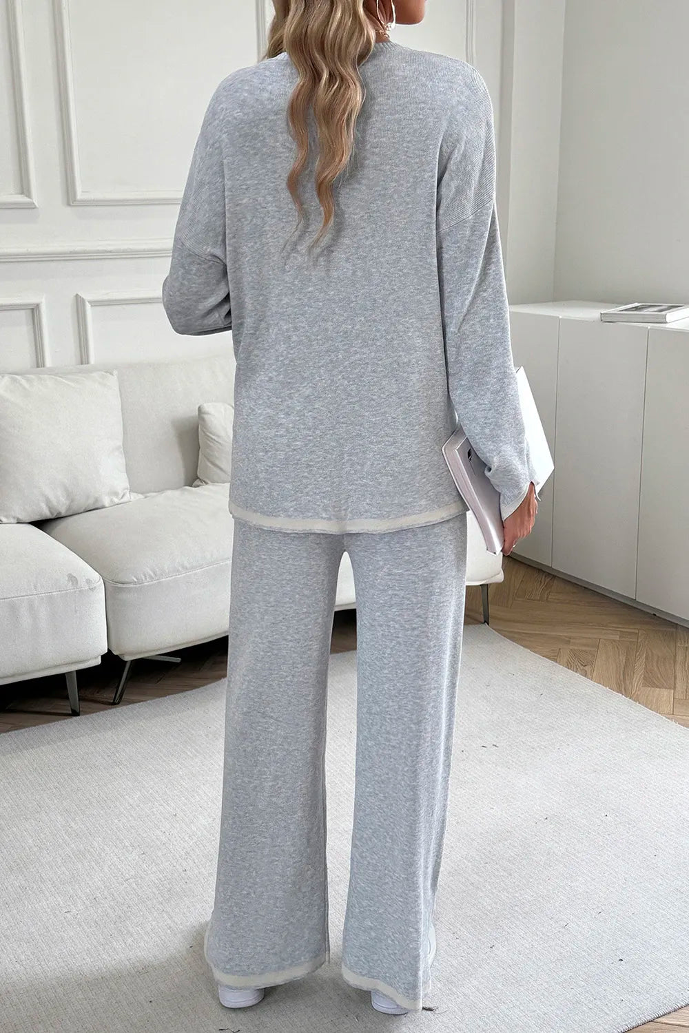 Person wearing a gray lounge set in a living room.