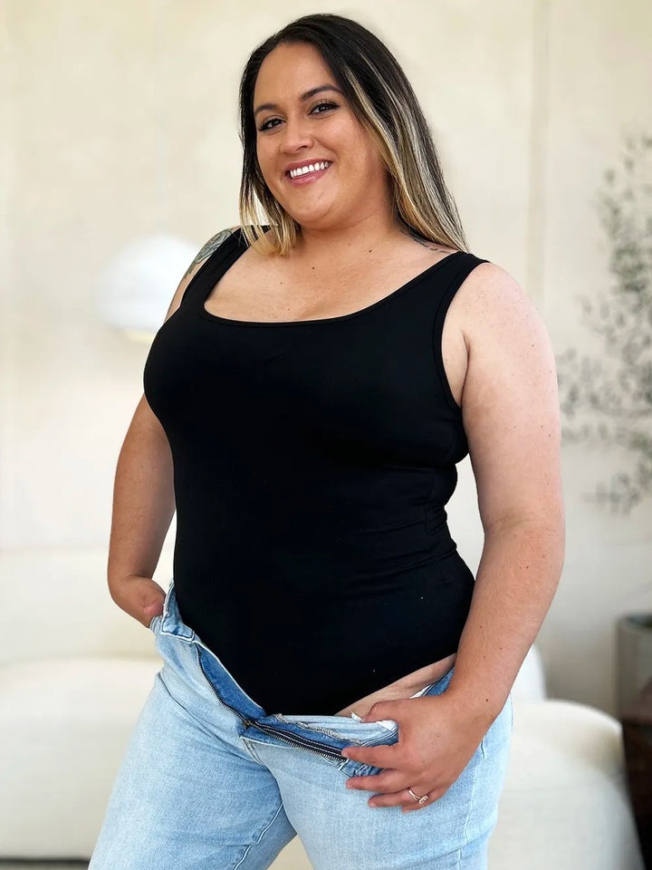 Person wearing a black tank top and light blue jeans indoors.