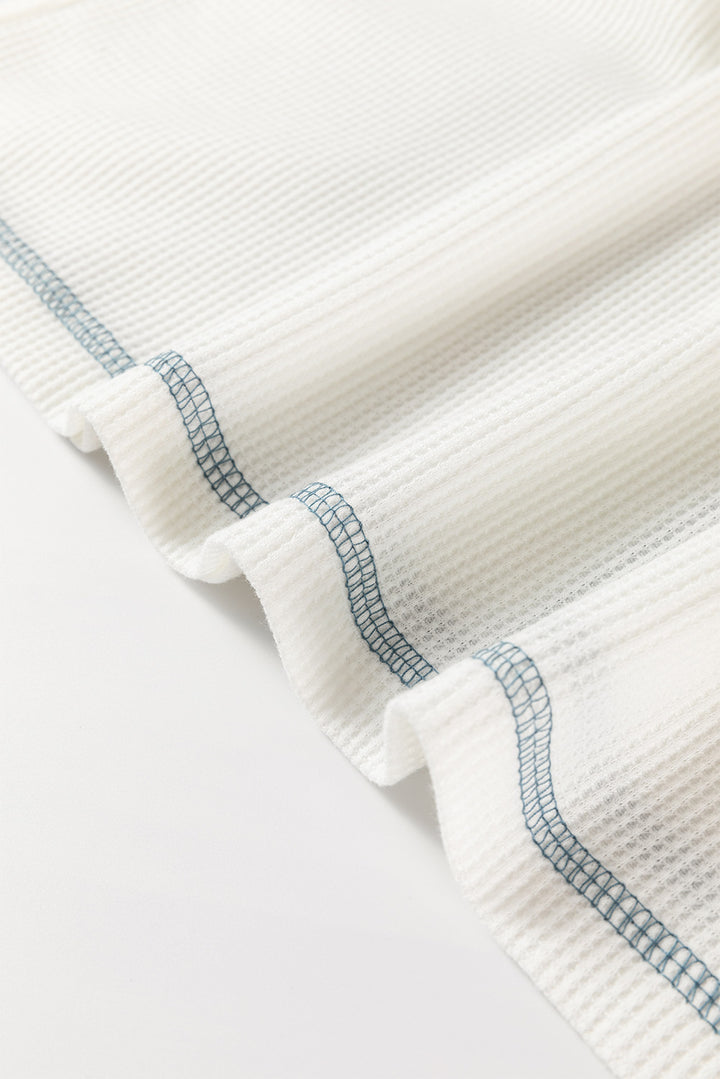 Close-up of a textured white fabric with blue stitching on a light gray background