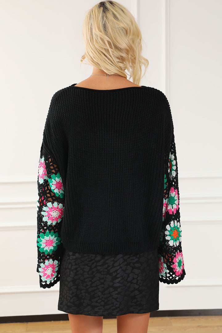 Black sweater with colorful floral patterns on sleeves against a white background