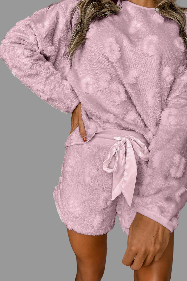 Person wearing a pink fleece outfit in front of a gray wall.