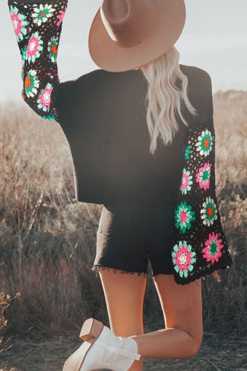 Person wearing a black outfit with colorful floral patterns in a natural setting