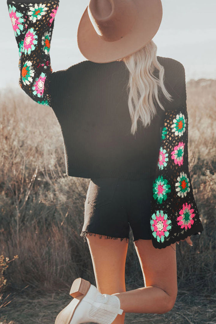 Person wearing a black outfit with colorful floral patterns in a natural setting