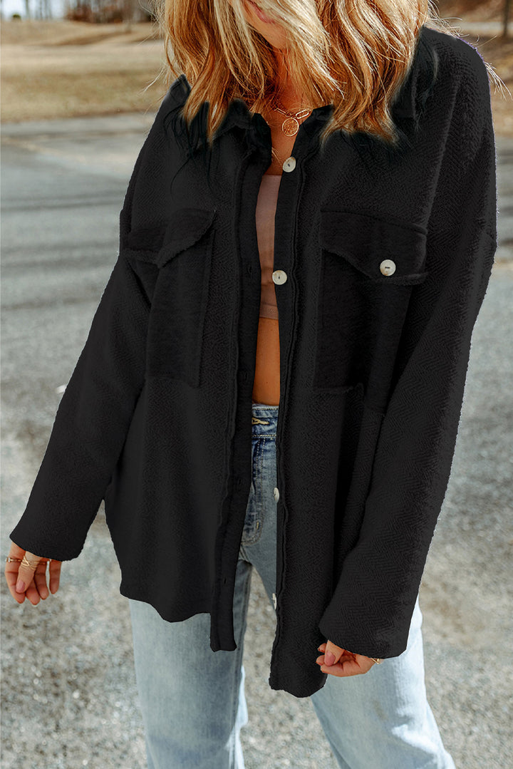 Person wearing a black jacket over a striped shirt with a blurred background