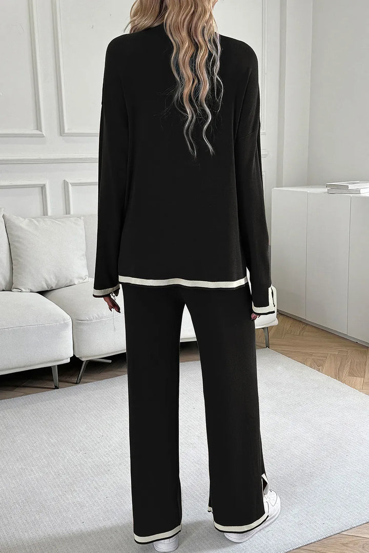 Person wearing a black outfit with white trim in a minimalistic room.