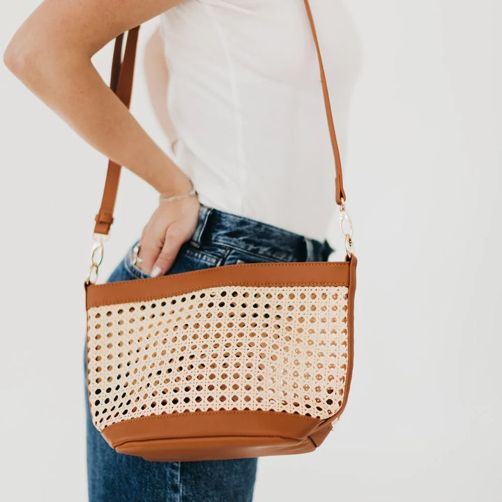 Women with woven cream-colored bag and brown accented edges and strap