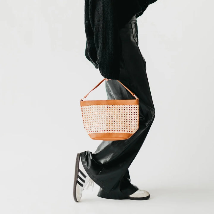Women with woven cream-colored bag and brown accented edges and strap