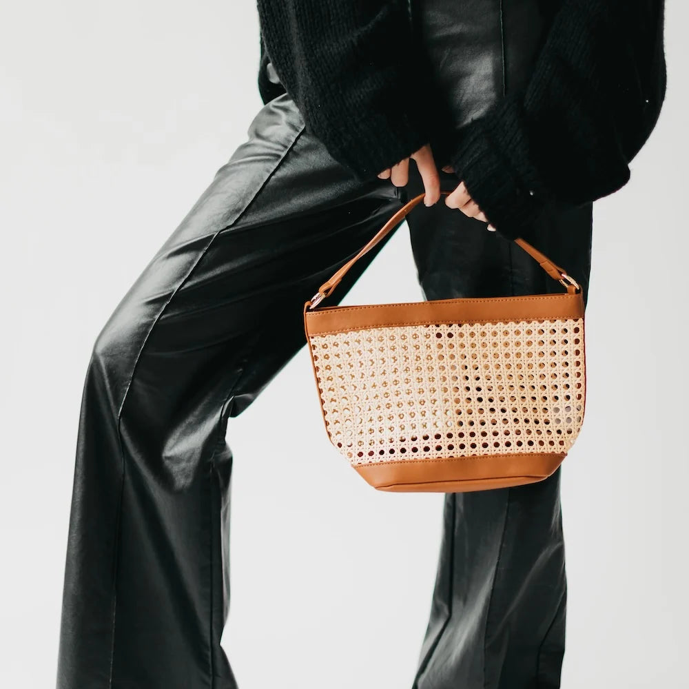 Women with woven cream-colored bag and brown accented edges and short strap