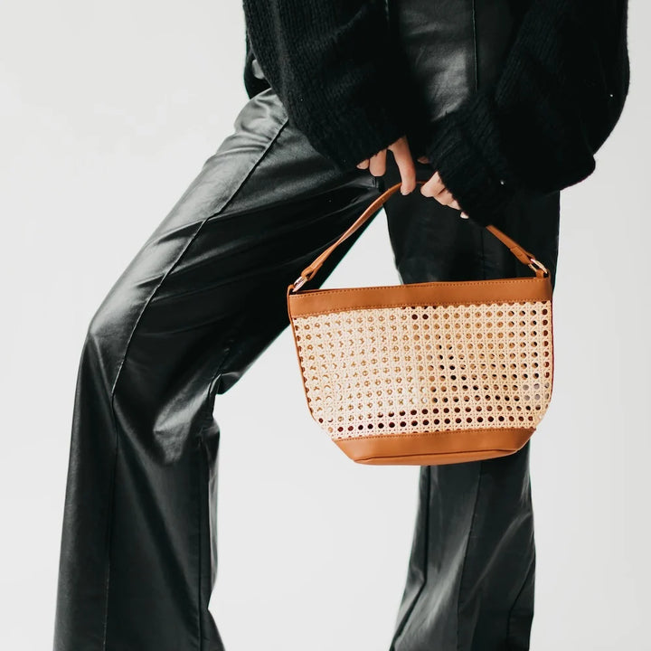 Women with woven cream-colored bag and brown accented edges and short strap