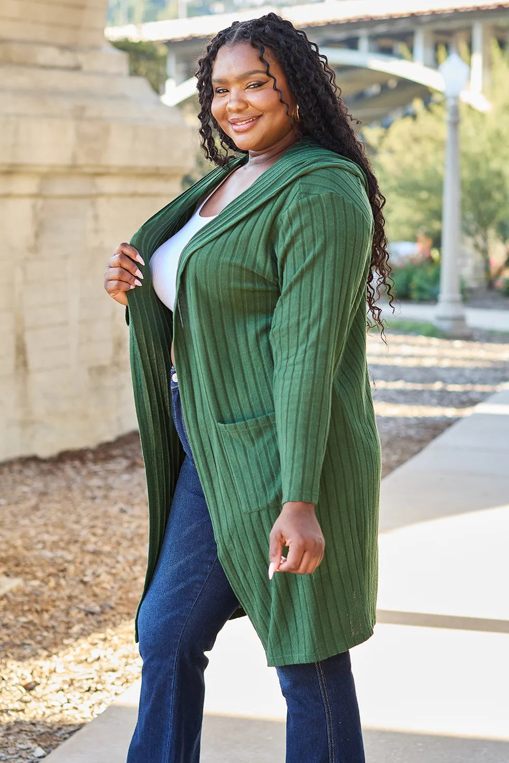 Woman wearing a green cardigan outdoors on a sunny day