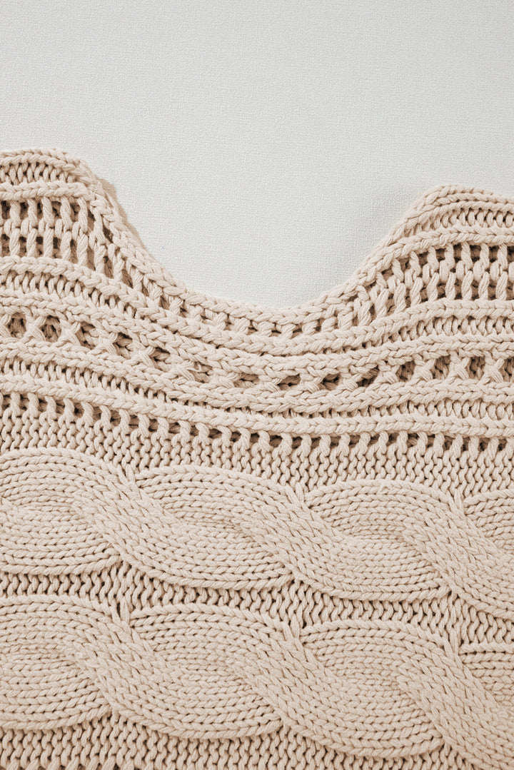 Close-up of a beige knitted garment with intricate patterns on a light gray background