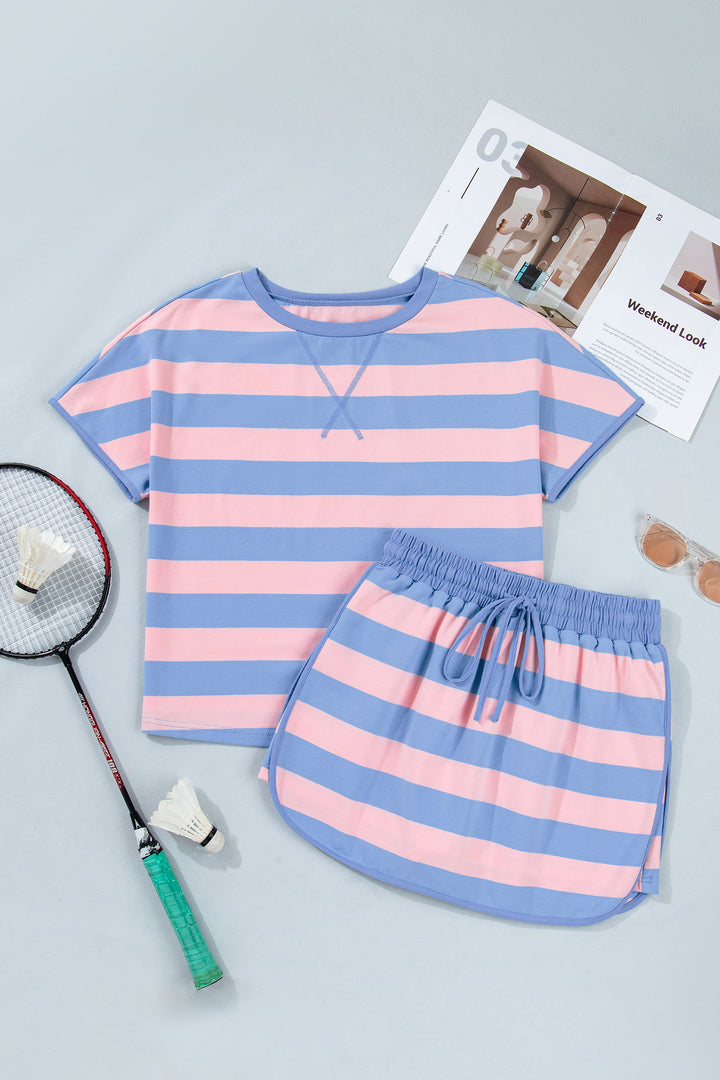 Pink and blue striped shirt and shorts set on a gray surface with a badminton racket and shuttlecock.