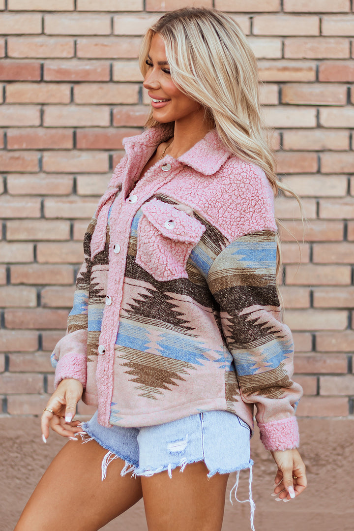 Woman wearing a pink patterned jacket against a brick wall