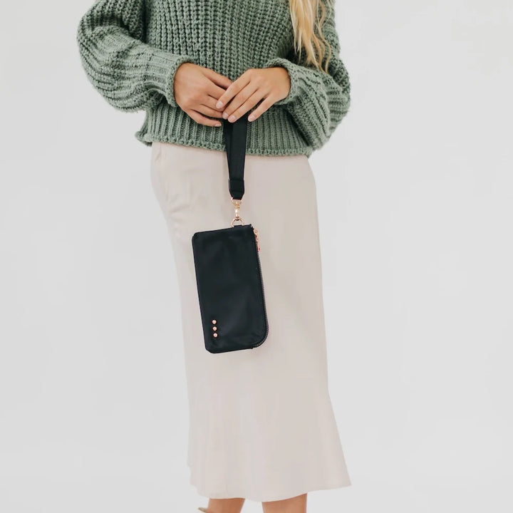 Woman holding a black wristlet wallet 