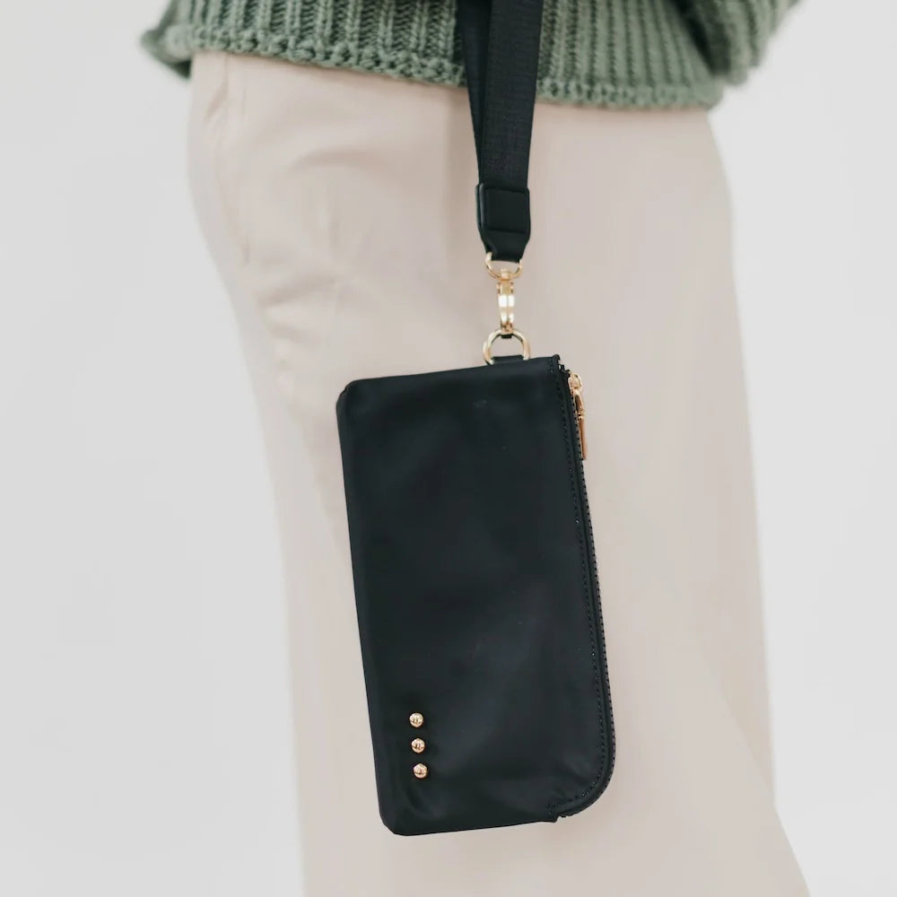 Black wristlet wallet hanging from arm