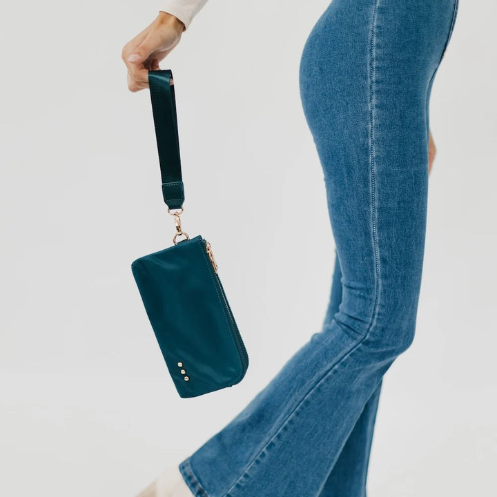 Person wearing jeans holding a teal wristlet wallet