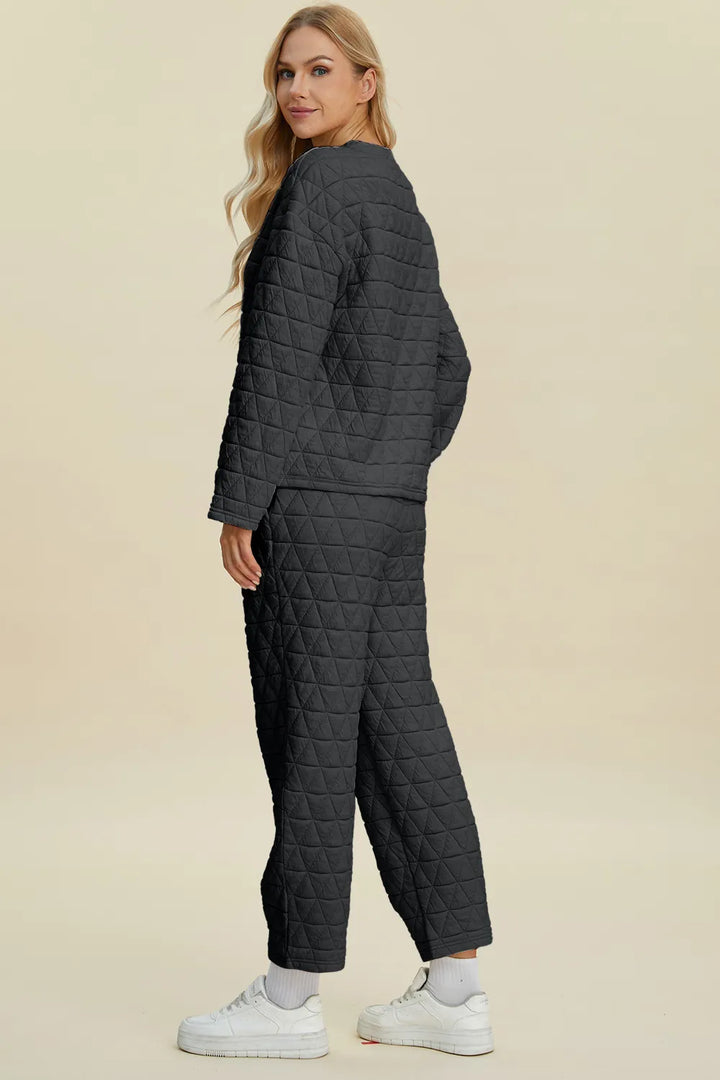 Woman wearing a dark gray quilted jacket and pants on a beige background