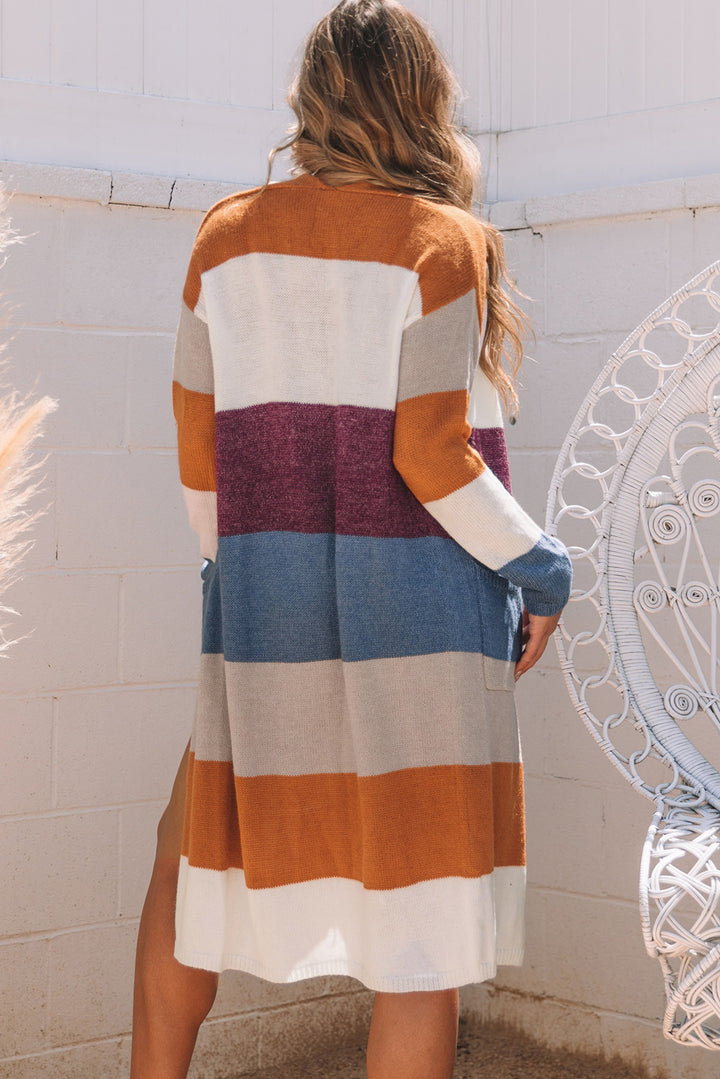 Woman wearing a colorful striped cardigan against a white wall.