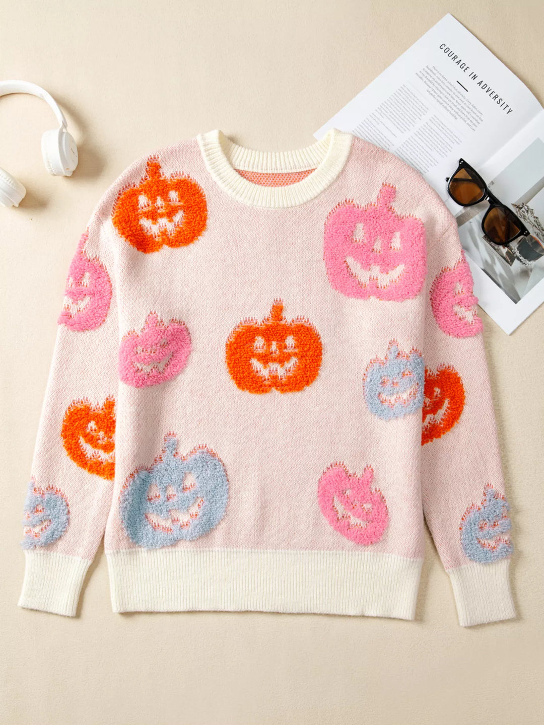A picture of a  a dusty pink sweatshirt with blue, pink. and orange pumpkins on it