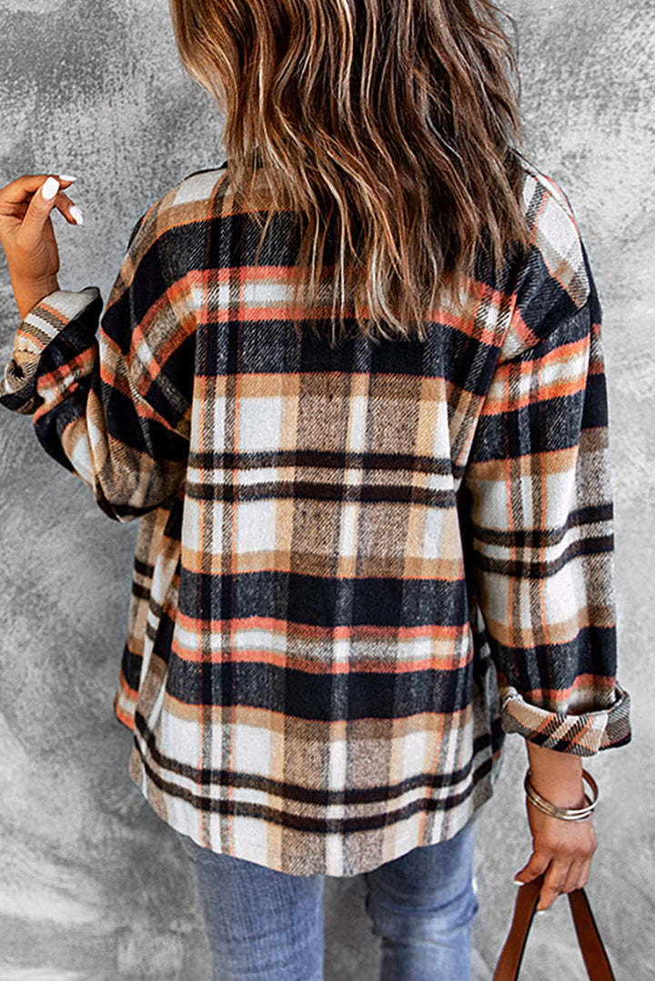 Person wearing a plaid shirt with rolled-up sleeves against a gray concrete wall.