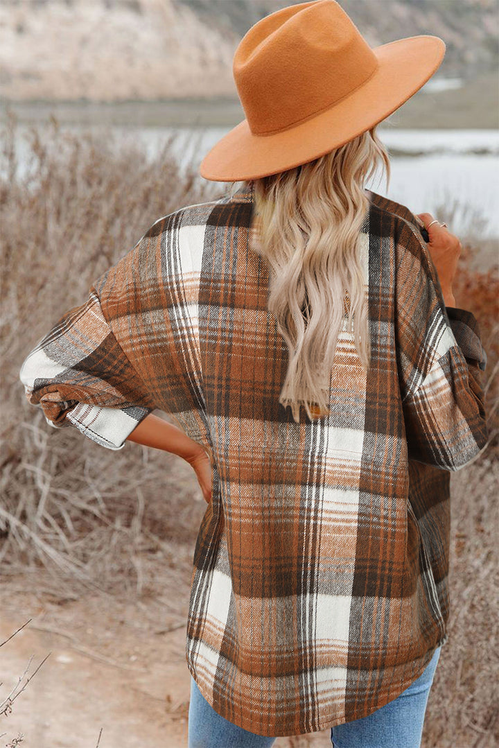 Person wearing a plaid shirt and orange hat with a scenic background