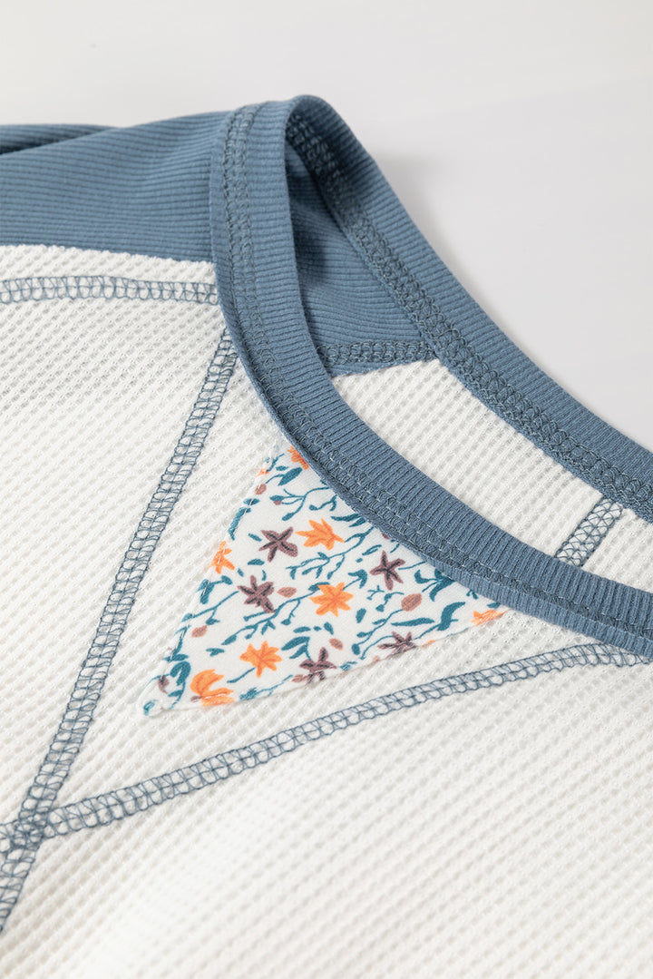Close-up of a textured fabric with floral pattern and blue trim on a light background