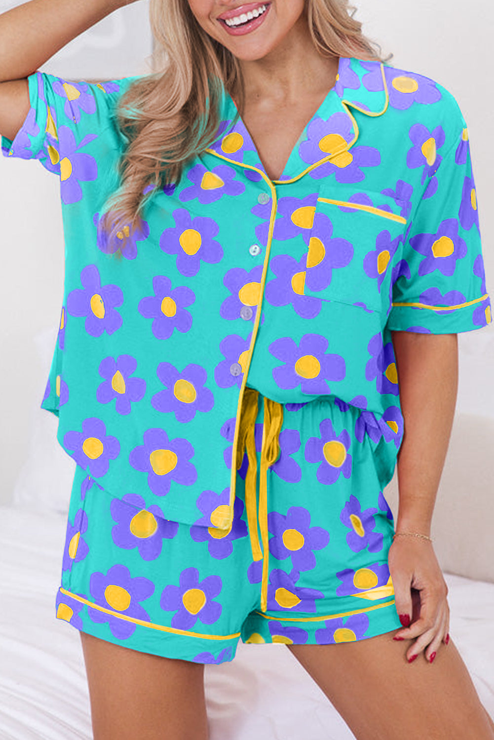Woman wearing a teal floral pajama set with yellow accents on a white background