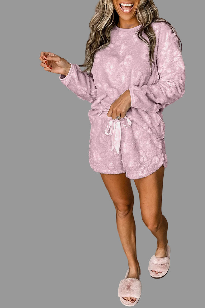 Woman in pink pajama set standing next to a gray wall.