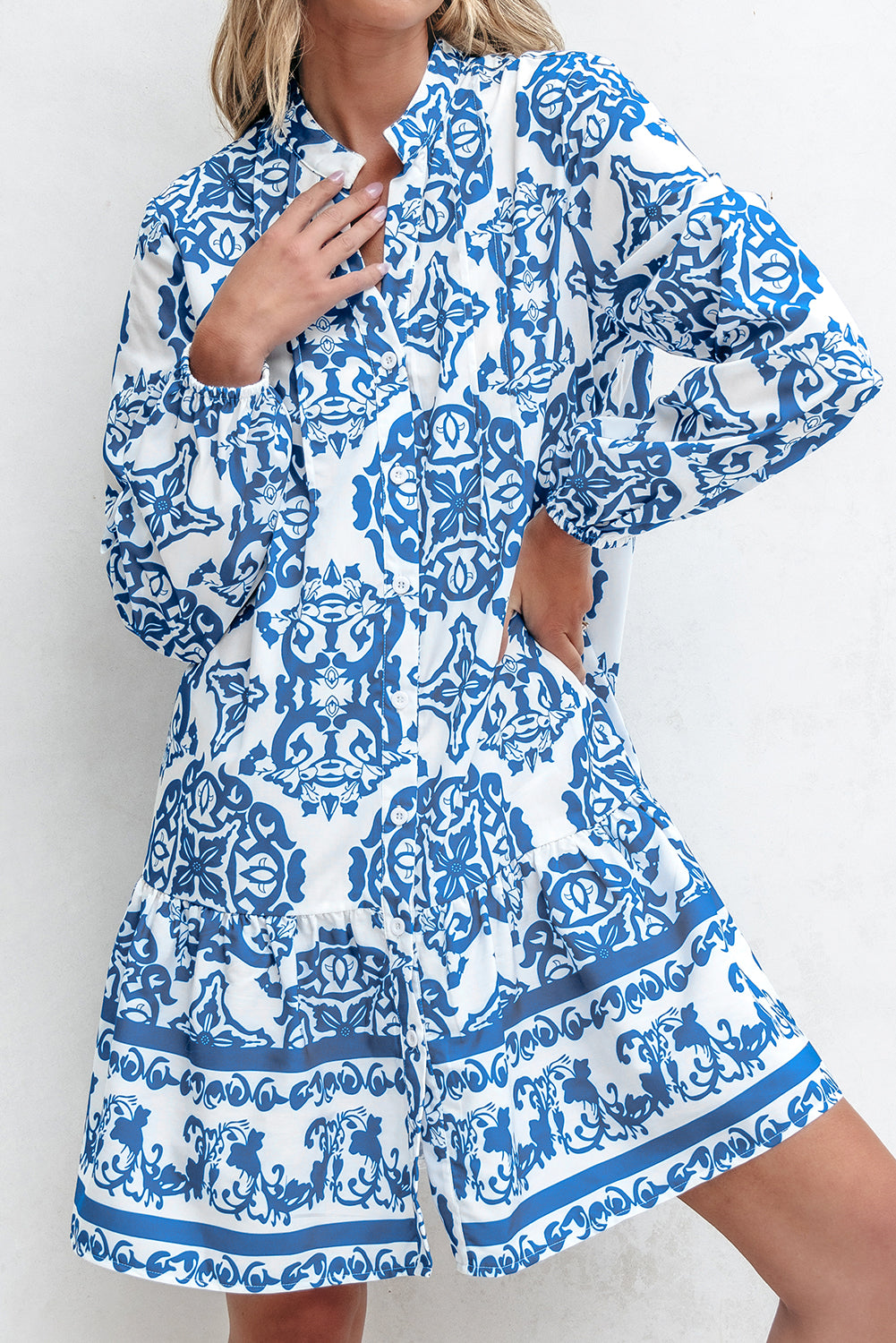 Woman wearing a blue and white patterned romper against a plain background