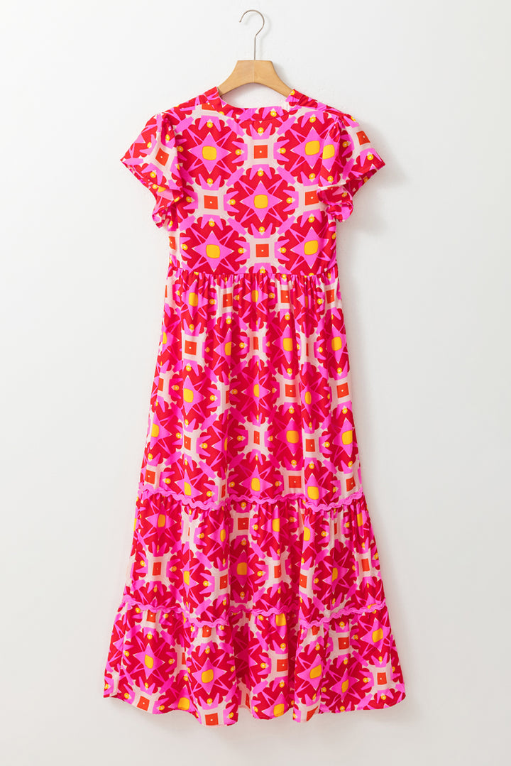 Pink patterned dress on a hanger against a white background
