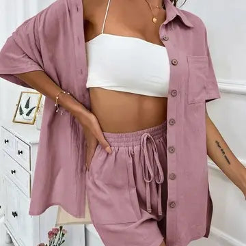 Person wearing a pink shirt, white crop top, and pink pants in a room.