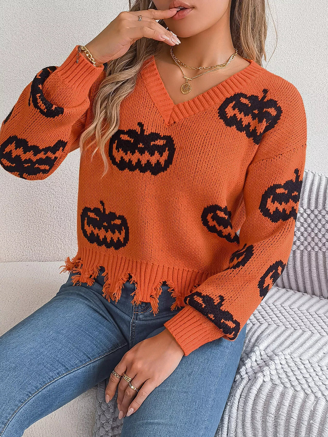 Women wearing orange sweater with black pumpkins on it while sitting