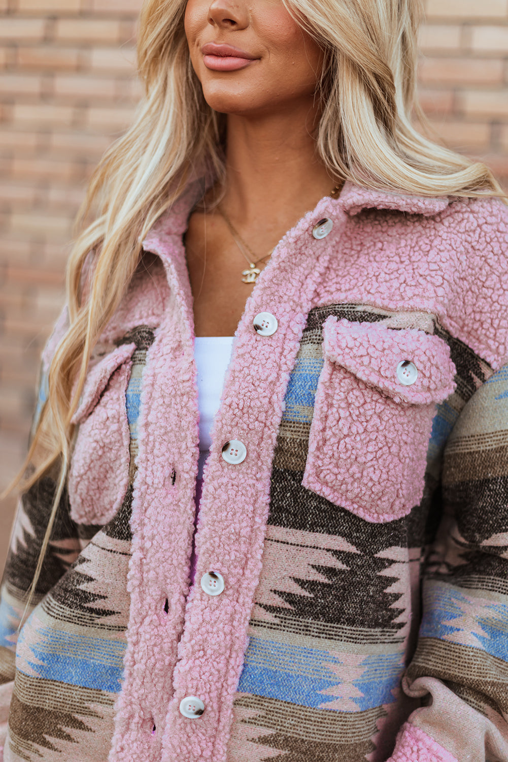 Close-up of a person wearing a pink sherpa-lined jacket with a patterned design.