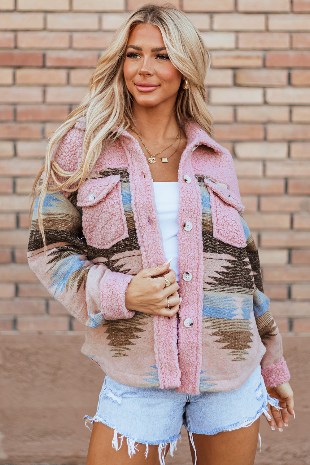 Woman wearing a patterned jacket in front of a brick wall