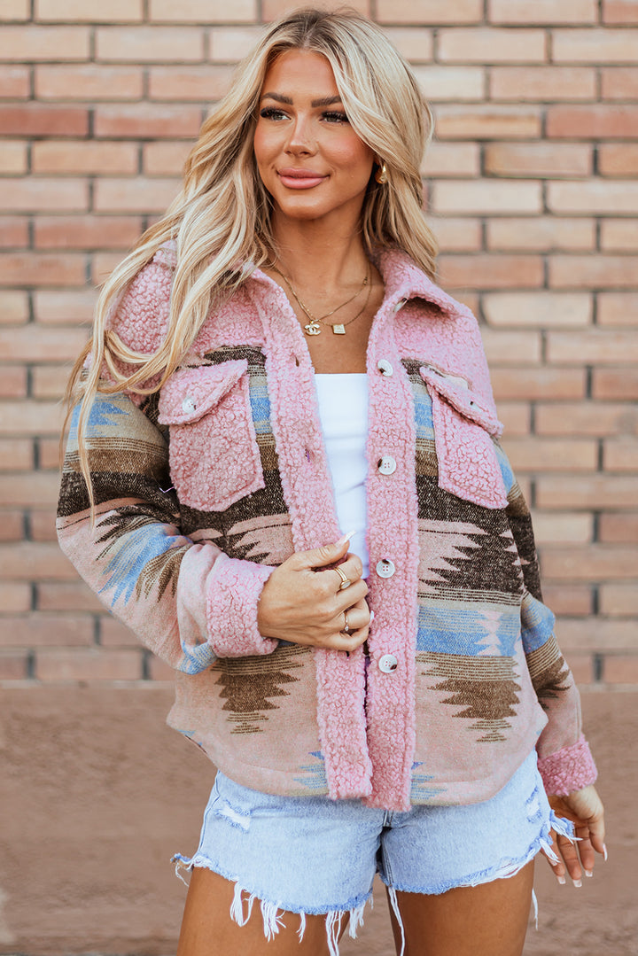 Woman wearing a patterned jacket in front of a brick wall