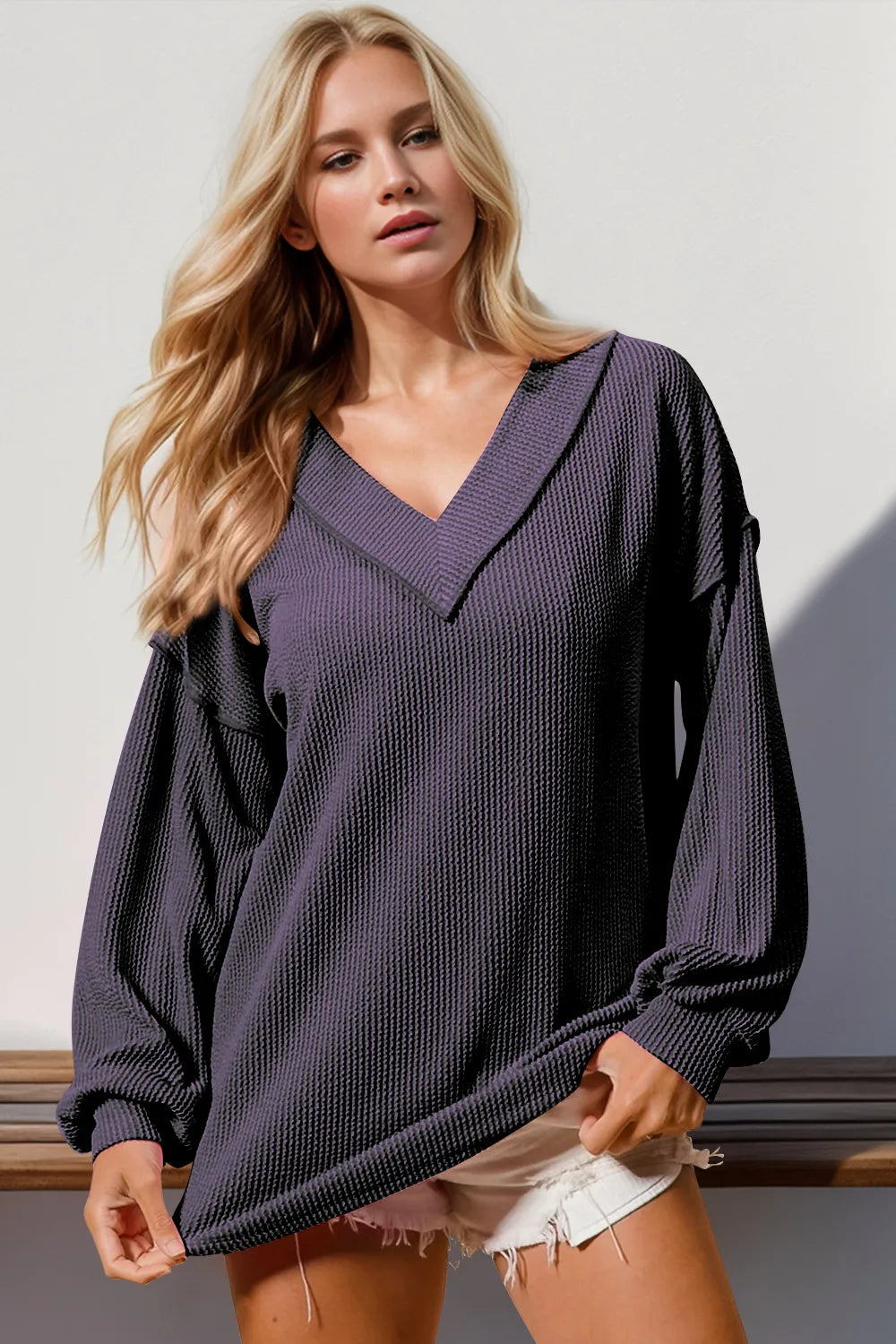 Woman wearing a dark purple oversized sweater against a white background