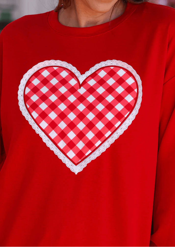 Red sweatshirt with a white checkered heart design on a blurred background